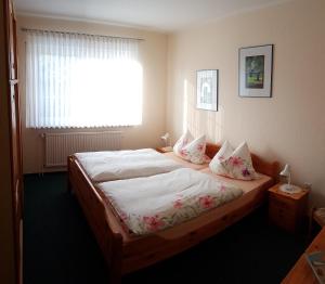 een slaapkamer met een bed met witte lakens en een raam bij Hausnordlicht FEWO 1 in Dornum