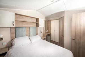 a bedroom with a white bed and wooden cabinets at Combe Martin Beach Holiday Park in Combe Martin