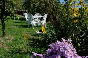 two chairs and a table in a garden with flowers at LES HAUTS DU CAUSSE in Grand-Mas