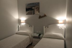 2 camas en una habitación con 2 lámparas en la pared en Hotel Los Palacios, en Formentera de Segura