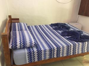 a bed with a blue and white comforter on it at Suite Airuma in Moreré