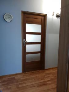 een houten deur in een kamer met een klok aan de muur bij Apartament Wyszynskiego in Białystok