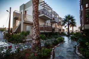 un complejo con una pasarela y palmeras en Ilian Beach & Apartments, en Rethymno