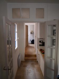 un couloir menant à une cuisine avec des placards blancs dans l'établissement Aux 4 FONTAINES, à Narbonne