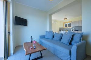 een woonkamer met een blauwe bank en een tafel bij Hilltop Residences in Kalamaki