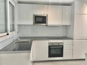 a white kitchen with a sink and a microwave at Casa en CARABAÑA a 30 minutos de MADRID in Carabaña