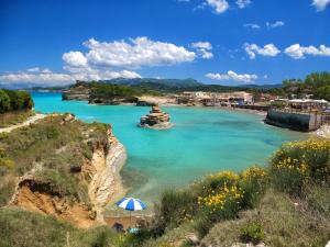 a beach with an umbrella in the water at Toula's Apartments in Sidari