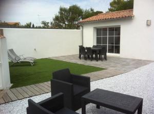 a patio with black chairs and a table and grass at La Fleur de Sel in La Flotte +10 photos
