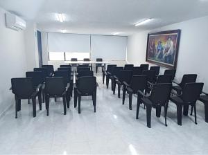 a room with black chairs and a white wall at Hotel San Nicolas in Bucaramanga