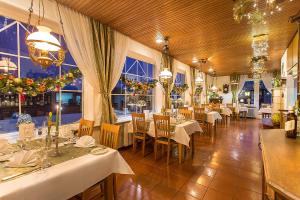 un restaurante con mesas y sillas blancas y ventanas en Hotel Diana en Feldberg