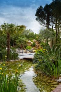 un jardín con estanque, bancos y plantas en Maison Pic, en Valence