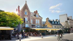 a man riding a bike down a city street at Hotel K'Loys in Paimpol