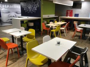 a restaurant with white tables and colorful chairs at ibis budget Dieppe Centre Port in Dieppe