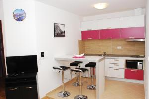 a kitchen with a island with bar stools and a tv at Budva Garden Apartments in Budva