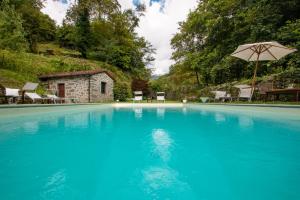 a large blue swimming pool with an umbrella at Holiday villa with pool, Mulino del Pita in Barga