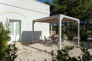 a patio with a table and chairs under a pavilion at Masseria Mongiò dell'Elefante in Otranto