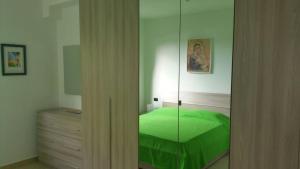 a bedroom with a green bed and a mirror at Villa sul mare Marinagri Resort in Policoro
