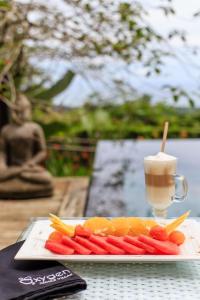 a plate of carrots and fruit on a table with a drink at Oxygen Jungle Villas & Spa in Uvita