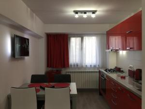 a kitchen with a table and chairs and a kitchen with red cabinets at Luxury Apartment in Galaţi +128 photos