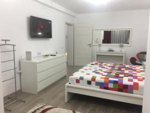 ein weißes Schlafzimmer mit einem Bett und einer Kommode in der Unterkunft Luxury Apartment in Galaţi
