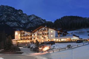 un grand bâtiment dans la neige la nuit dans l'établissement Hotel Dosses, à Tires