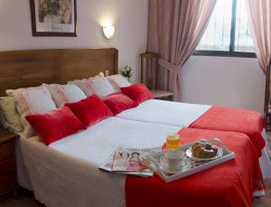 a hotel room with a bed with a tray of food on it at Hotel Praderón in San Sebastián de los Reyes