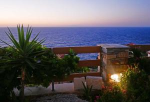 een uitzicht op de oceaan vanuit een tuin bij zonsondergang bij Anemi Apartments in Armenistis