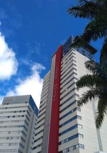 um edifício alto branco e vermelho com uma palmeira em Trade Hotel em Juiz de Fora