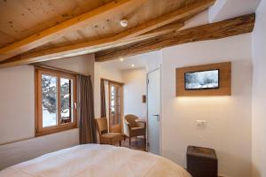 a bedroom with a bed and a desk and a window at Hotel Edelweiss in Blatten im Lötschental