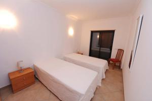 a bedroom with two beds and a chair and a window at Quarteira Beach in Quarteira