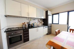 a kitchen with white cabinets and a stove and a table at Quarteira Beach in Quarteira
