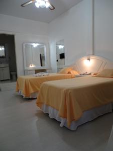 two beds in a white room with yellow sheets at Hotel Crespo in Crespo