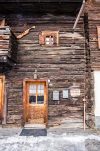 Un edificio de madera con una puerta y un cartel. en Appartamenti Touring, en Livigno