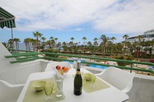 a table with a bottle of wine and glasses on a balcony at Luxury Apartments in first beach line with pool in Adeje