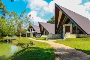 a house with a gambrel roof next to a river at Liyya Water Villas in Dambulla