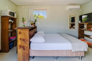 1 dormitorio con 1 cama grande con sábanas blancas en Pousada Container Eco Guarda en Guarda do Embaú