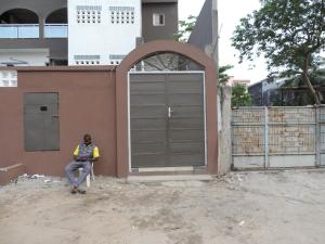 um homem sentado numa cadeira em frente a uma garagem em Happy Welcome Bietry 2 em Abidjan