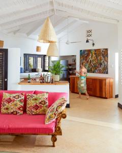 a living room with a red couch and a woman in a kitchen at Jakes Hotel in Treasure Beach