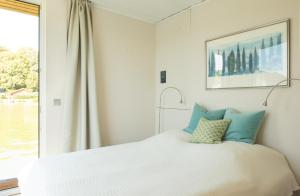 a white bed with blue pillows in a bedroom at Marina Hausboote und Seelodge in Berlin