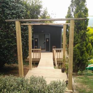 a wooden walkway leading to a black house at starry nights tree house in Waikino +5 photos
