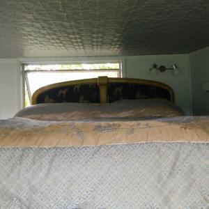 a bed in a small room with a window at starry nights tree house in Waikino