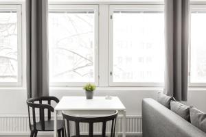 a living room with a table and two windows at Hiisi Homes Helsinki Haaga in Helsinki