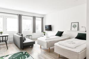 uma sala de estar branca com um sofá e uma cadeira em Hiisi Homes Helsinki Haaga em Helsinque