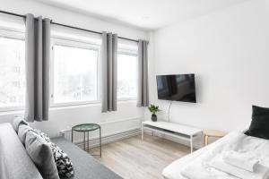 a white living room with a couch and a tv at Hiisi Homes Helsinki Haaga in Helsinki