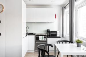 cocina con armarios blancos, mesa y sillas en Hiisi Homes Helsinki Haaga en Helsinki