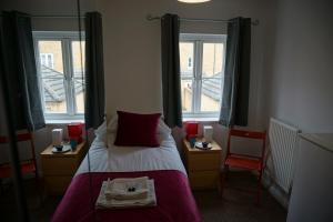 a bedroom with a bed with two chairs and two windows at The Coach House in Bristol