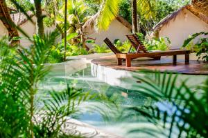 a resort pool with two chairs and a bench at Serena Tulum - Adults Only in Tulum