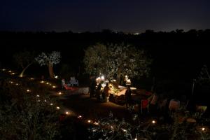 een groep mensen die 's nachts rond een tafel zitten bij Pensão Agrícola in Cabanas de Tavira