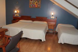 a bedroom with two beds and a table and a chair at Hotel El Castillo in Ponferrada