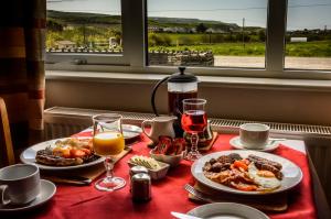 einen Tisch mit zwei Teller Essen und Gläsern Wein in der Unterkunft The Pipers Rest in Doolin